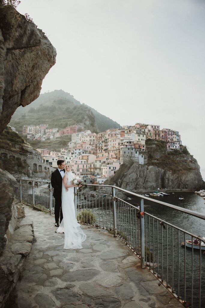 Lovely couple standing on a pathway overlooking the village of Manarola in Cinque Terre, Italy