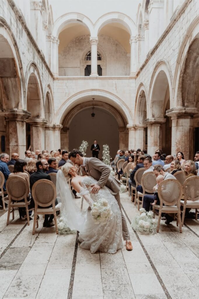 Bride and groom in a dramatic dip kiss at their wedding ceremony in Sponza Palace, Dubrovnik