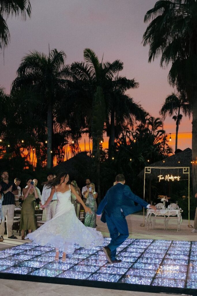 Bride and groom dancing at a sunset beach ceremony 